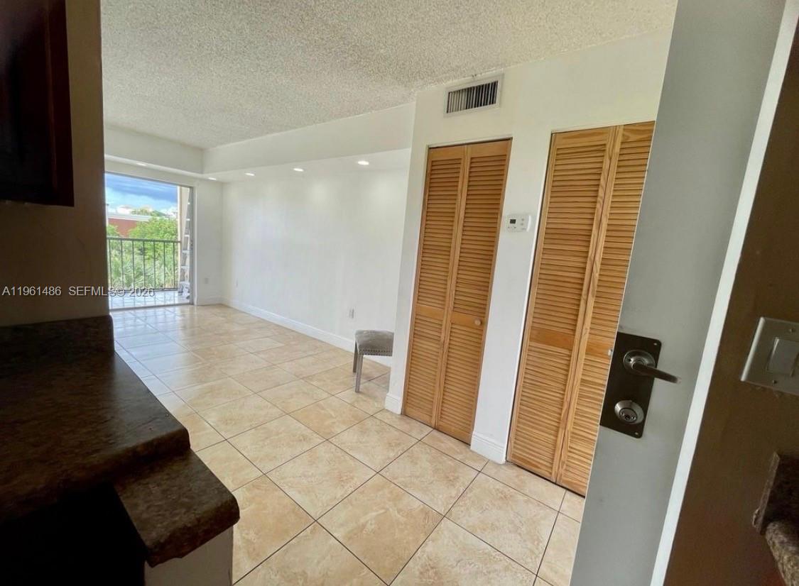 An interior view of a room with tiled floors, louvered closet doors, and a balcony — 9405 W Flagler St # D403, Miami FL 33174, MIAMI, FL