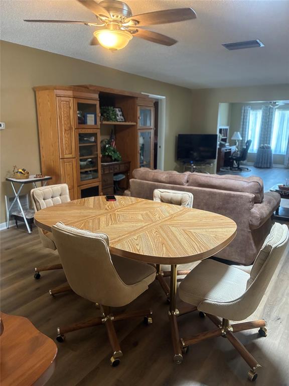 A dining area with a wooden table and rolling chairs sits before a living room — 1674 S LAKE AVENUE UNIT 6, CLEARWATER, FL