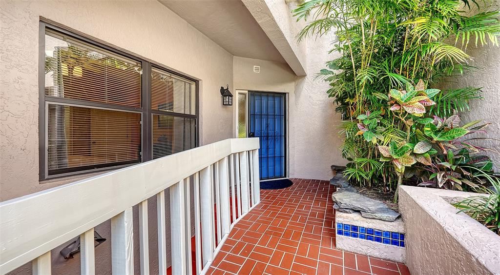 A walkway with a white railing leads to a blue front door beside a planter — 1632 STARLING DRIVE UNIT 101, SARASOTA, FL