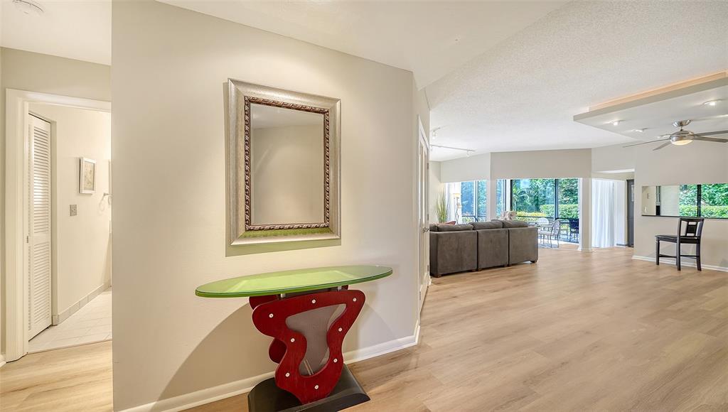 A hallway with a glass-topped console table and mirror leads into an open living area — 1632 STARLING DRIVE UNIT 101, SARASOTA, FL