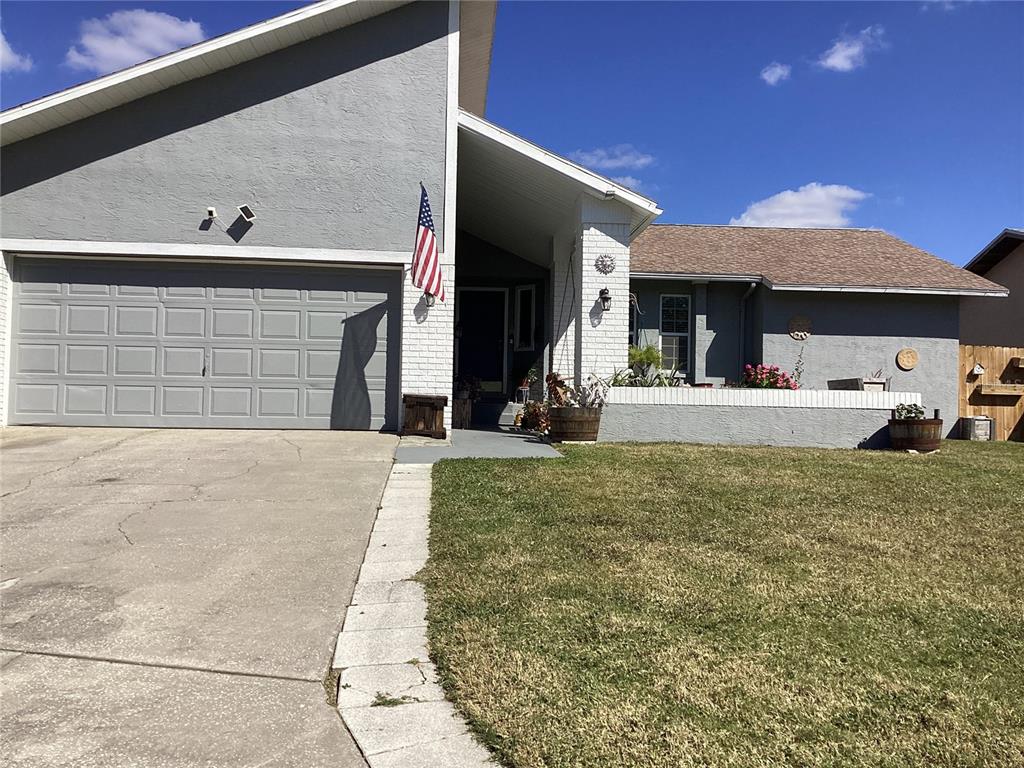 A gray house with a two-car garage, white brick accents, and a front lawn — 6426 DRAKE COURT, NEW PORT RICHEY, FL