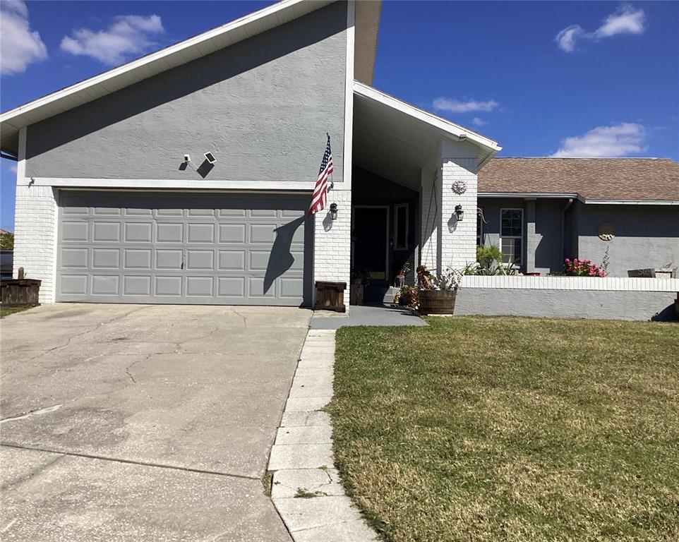 A gray house with a white brick facade, a two-car garage, and a front lawn — 6426 DRAKE COURT, NEW PORT RICHEY, FL