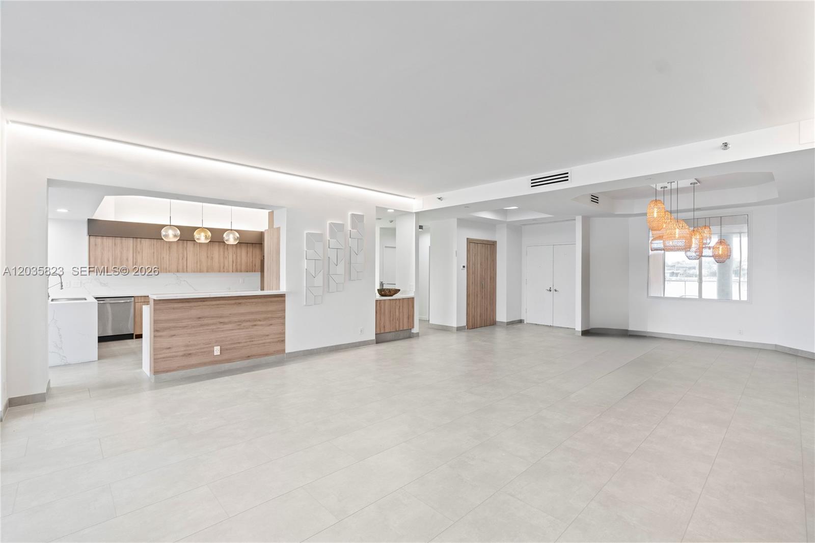A modern, open-concept living area features light tile flooring, a kitchen island, and pendant lighting — 3801 NE 207th St, Aventura FL 33180, AVENTURA, FL
