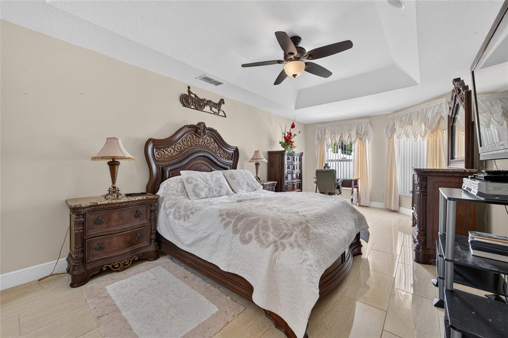 A bedroom features a dark wood bed frame, tile flooring, and a tray ceiling — 1418 PRINCESS PAULA DRIVE, PORT ORANGE, FL