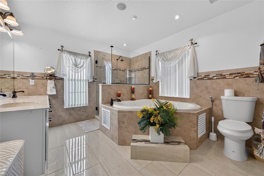 A bathroom features a tiled soaking tub, a glass-enclosed shower, and a white toilet — 1418 PRINCESS PAULA DRIVE, PORT ORANGE, FL