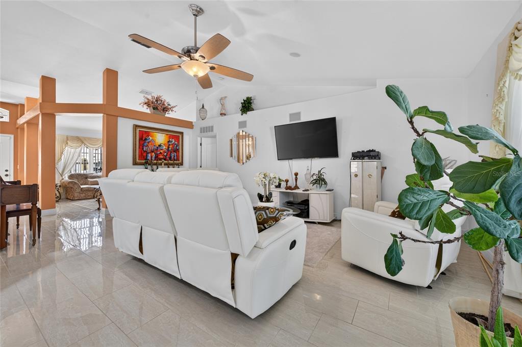 A living room features white leather furniture, a ceiling fan, and tile flooring — 1418 PRINCESS PAULA DRIVE, PORT ORANGE, FL