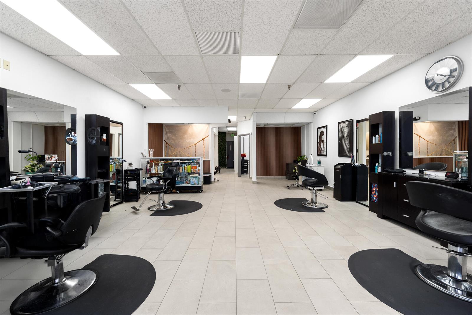 A hair salon featuring multiple styling stations, black chairs, mirrors, and light-colored tile flooring — 4608 South Jog Road, FL 33467, FL