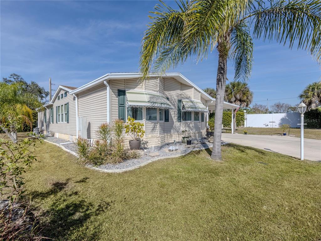 A single-story beige mobile home with a palm tree and a concrete driveway — 236 NATURES WAY, NORTH PORT, FL
