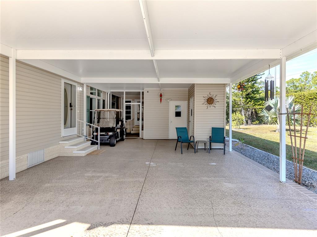 A covered carport features a concrete floor, two chairs, and a parked golf cart — 236 NATURES WAY, NORTH PORT, FL