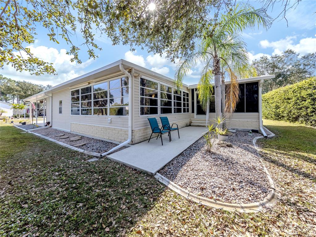 The exterior of a single-story home features light siding, large windows, and a concrete patio — 236 NATURES WAY, NORTH PORT, FL