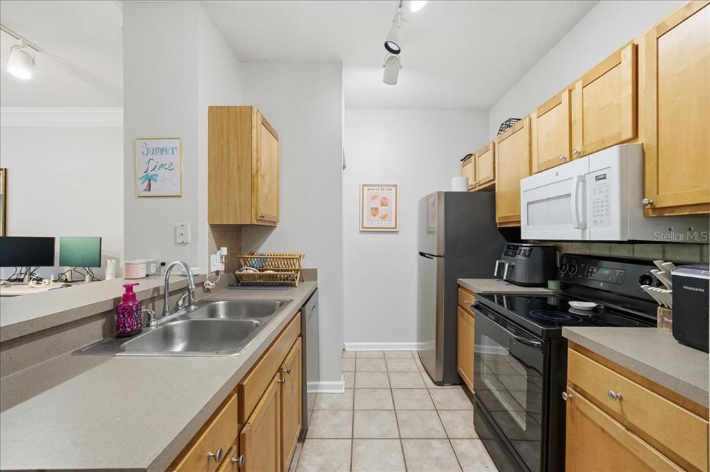 A kitchen with light wood cabinets and gray countertops overlooks a living room area — 4207 S DALE MABRY HIGHWAY UNIT 5307, TAMPA, FL