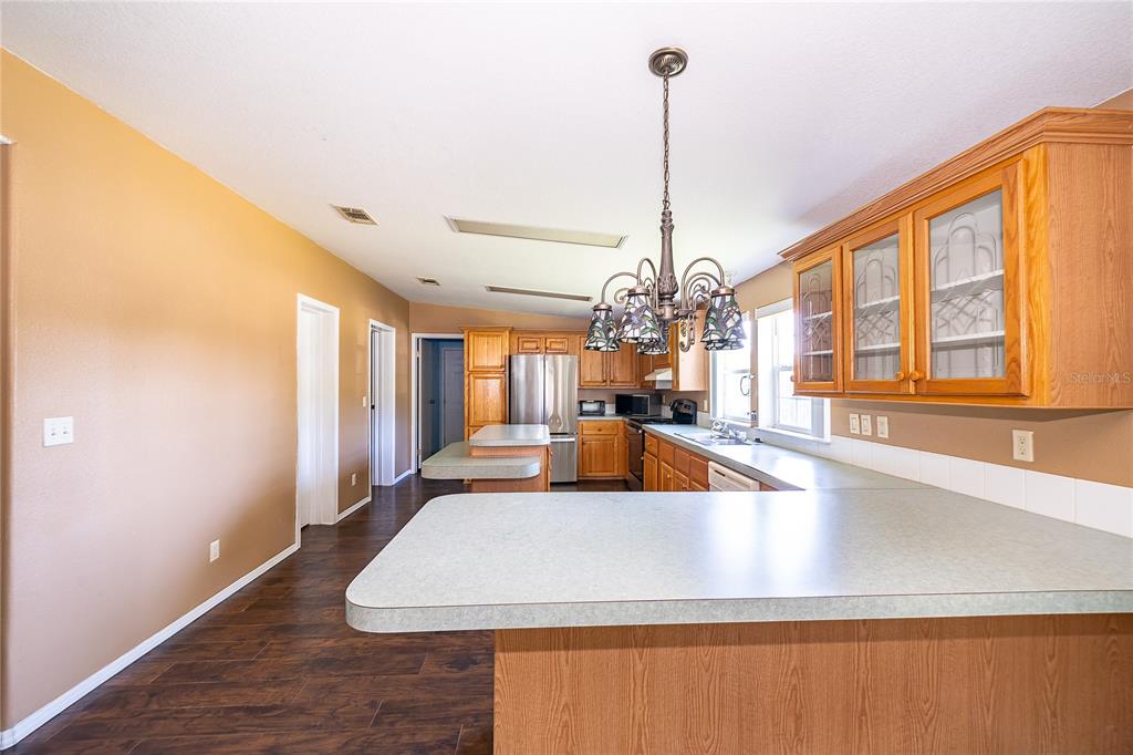 A kitchen with wood cabinets, a peninsula countertop, and a hanging light fixture — 800 GEE CREEK COURT, CASSELBERRY, FL