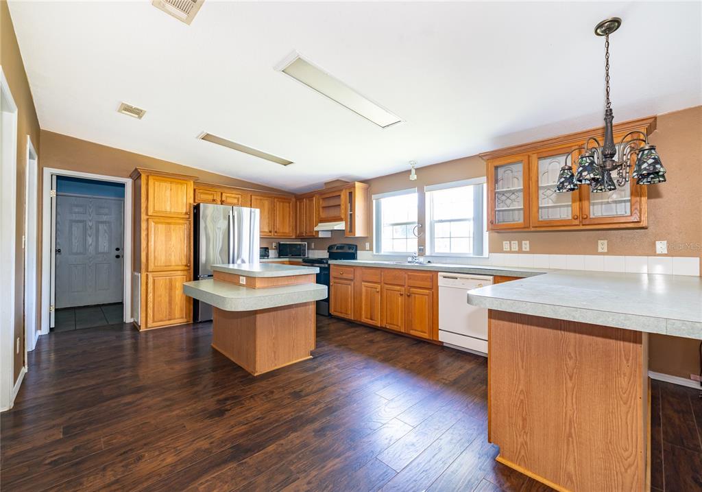 A kitchen with wood cabinets, laminate countertops, stainless steel appliances, and dark wood-look flooring — 800 GEE CREEK COURT, CASSELBERRY, FL