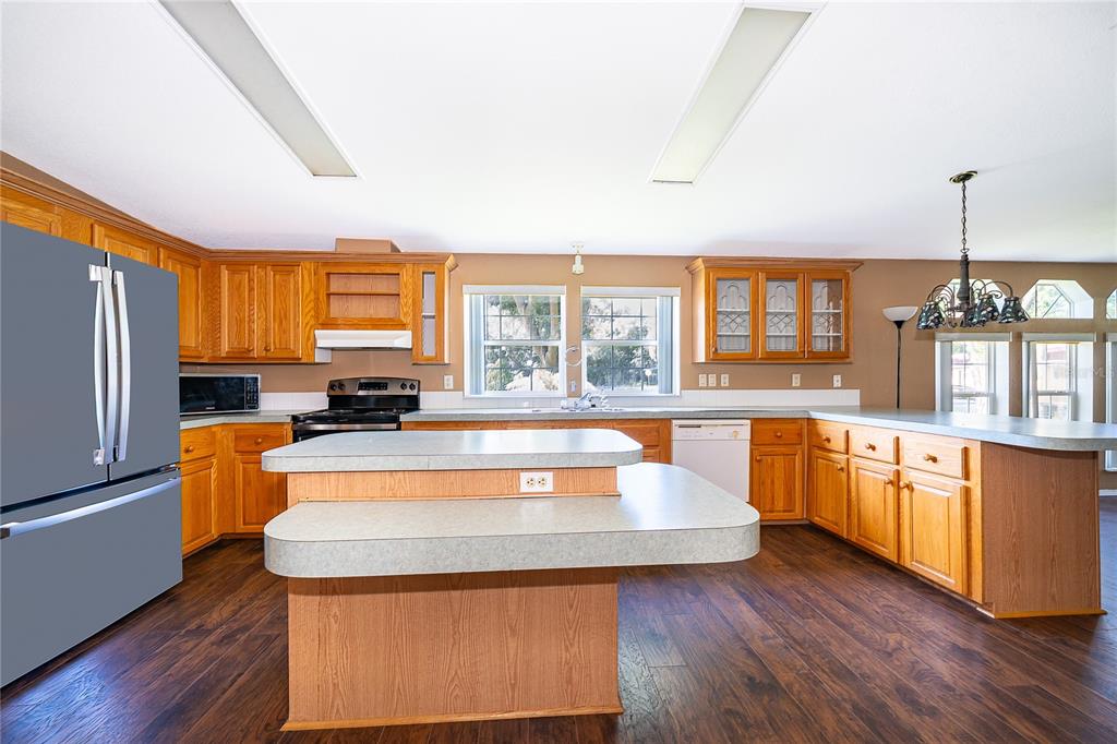 A kitchen features wood cabinets, a two-tiered island, and dark wood-look flooring — 800 GEE CREEK COURT, CASSELBERRY, FL