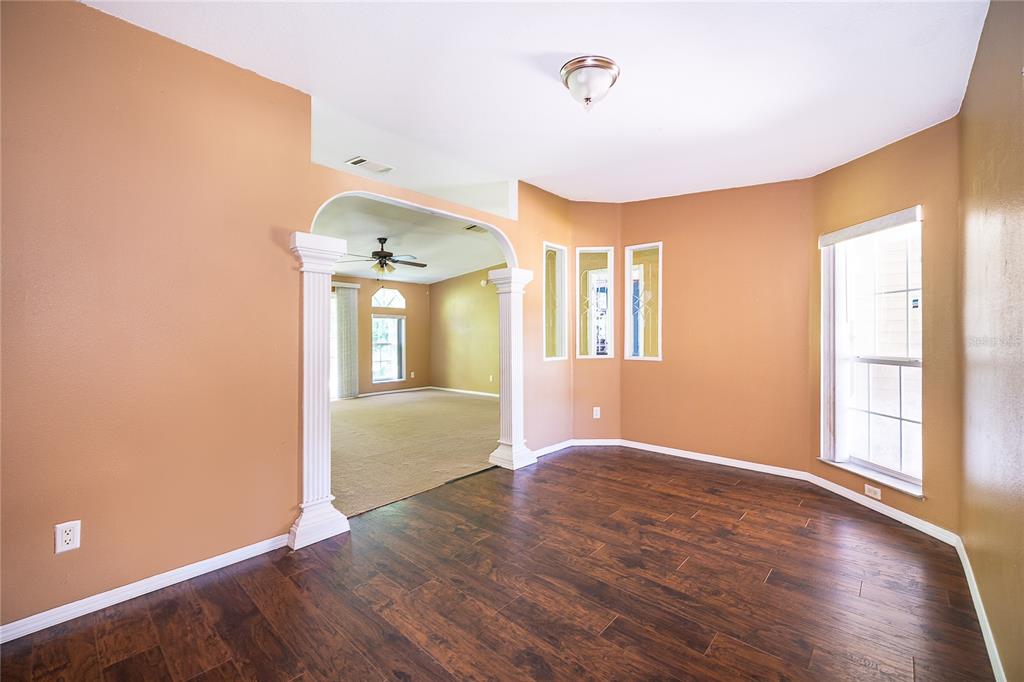 A dining room with dark wood flooring, tan walls, and an arched entryway with columns — 800 GEE CREEK COURT, CASSELBERRY, FL
