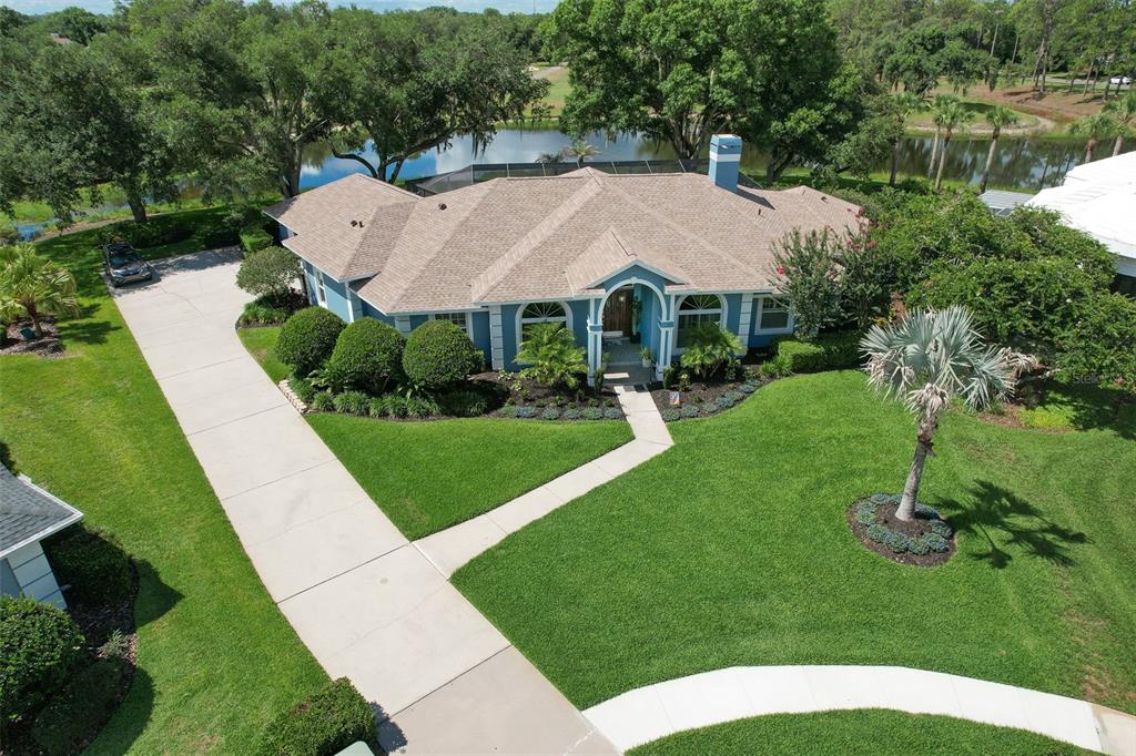 An aerial view of a blue house with a tan roof, driveway, and backyard pond — 5103 BROKEN SOUND LANE, VALRICO, FL