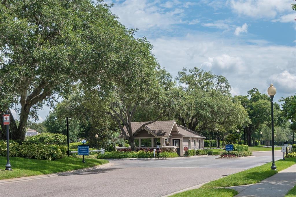 A gated community entrance features a small guardhouse surrounded by large trees and landscaping — 5103 BROKEN SOUND LANE, VALRICO, FL