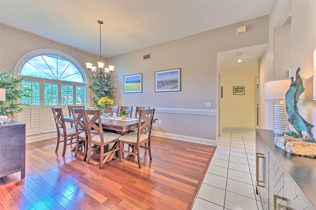 A dining room with hardwood floors, a wooden table, and a large arched window — 5103 BROKEN SOUND LANE, VALRICO, FL