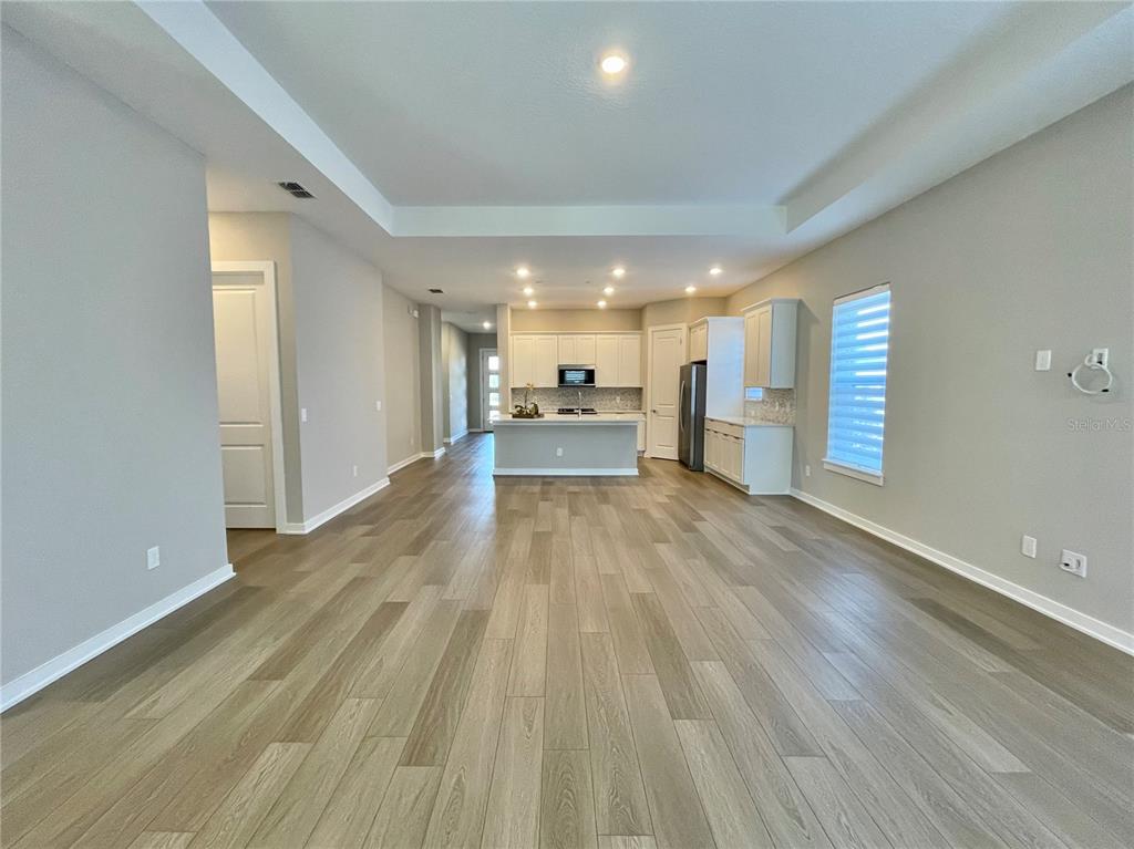 An open-concept kitchen and living area feature light wood-look flooring and white cabinetry — 6958 BRIDGMAN STREET, ORLANDO, FL