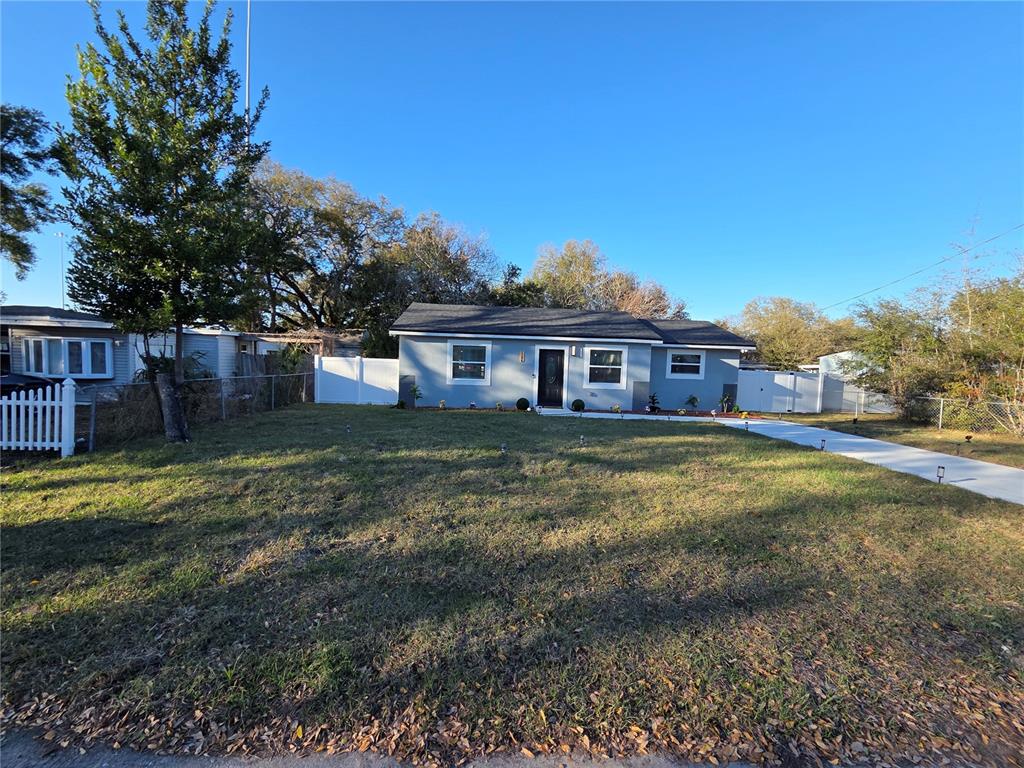 A single-story house with gray siding and a white fence sits on a grassy lot — 1106 VALENCIA ROAD, PLANT CITY, FL