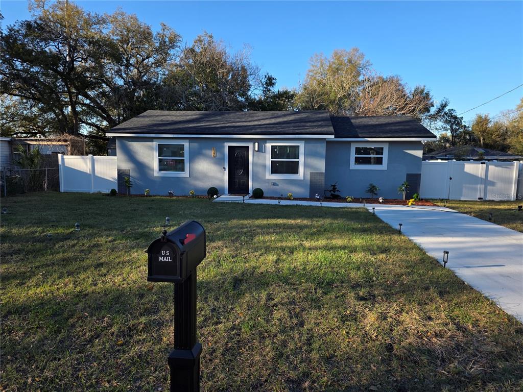 A single-story gray house with a dark roof, white trim, and a concrete driveway — 1106 VALENCIA ROAD, PLANT CITY, FL