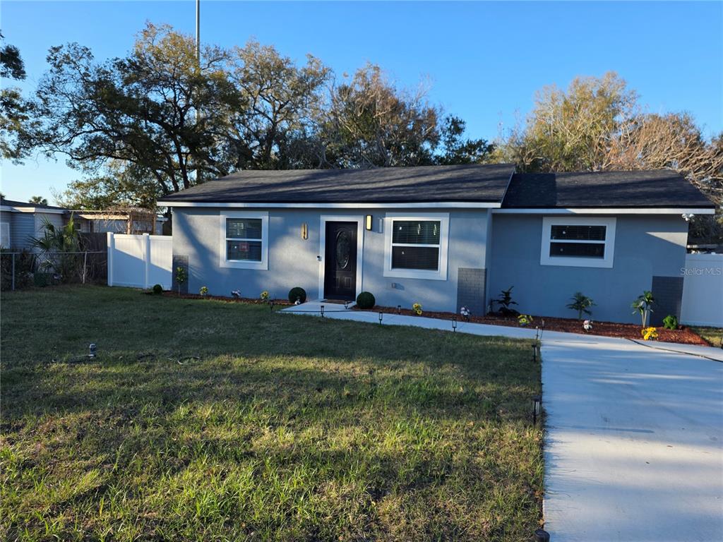 A single-story gray house with a dark roof, white trim, and a concrete driveway — 1106 VALENCIA ROAD, PLANT CITY, FL
