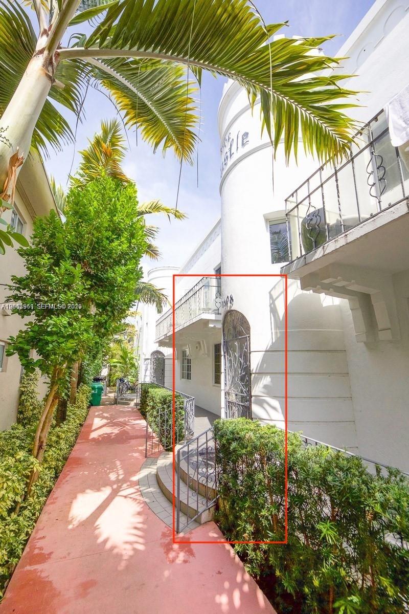 An exterior view of a white building with a gated entrance and a balcony — 1508 Meridian Ave, Miami Beach FL 33139, MIAMI BEACH, FL