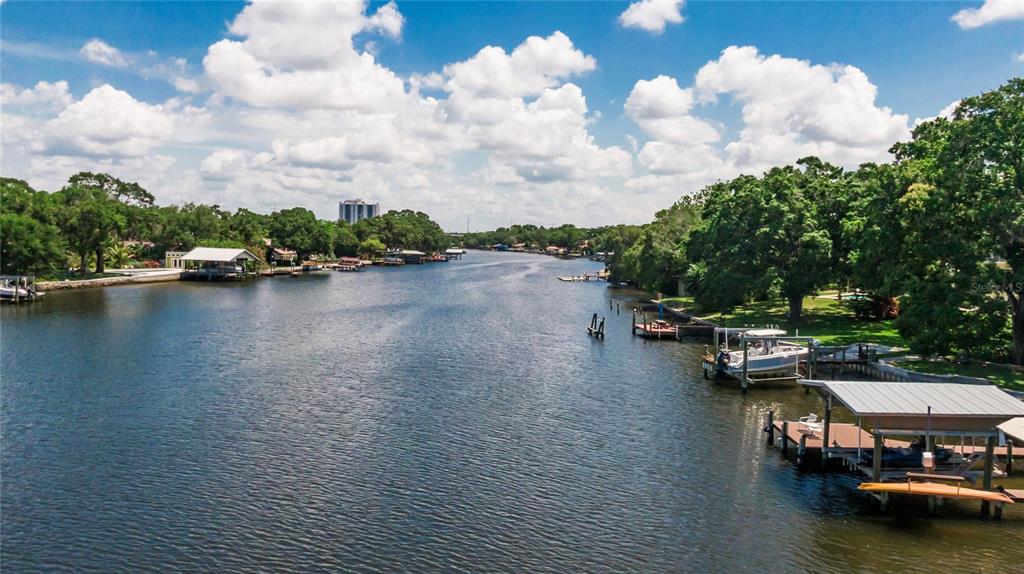An aerial view of a canal lined with boat docks, lush trees, and residential properties — 4033 N RIVER VIEW AVENUE, TAMPA, FL