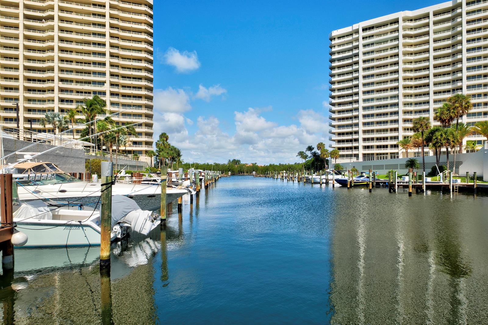 A canal lined with boat slips and tall residential buildings under a blue sky — BOCA RATON, FL