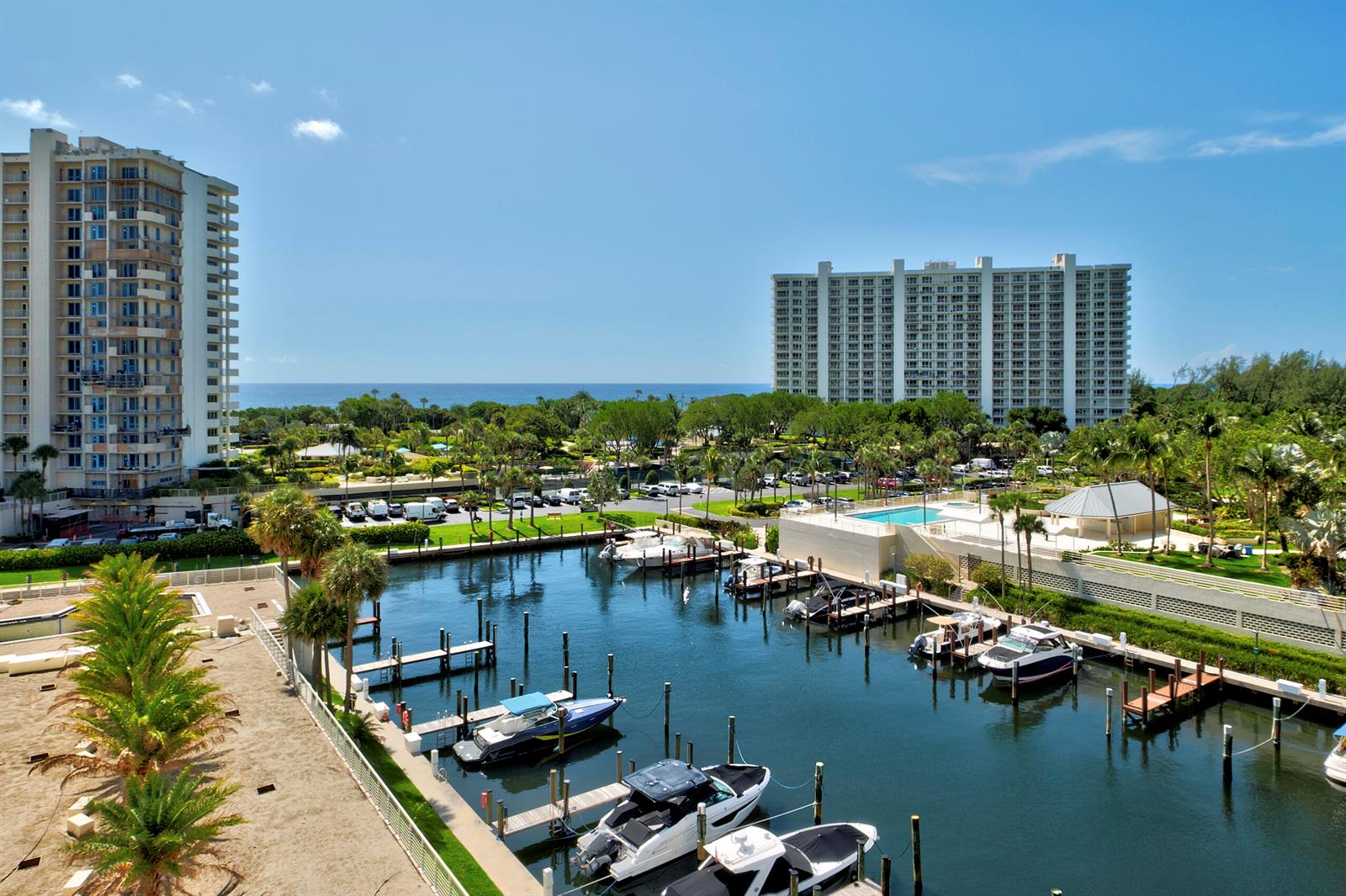 An elevated view of a marina with several boats docked in front of two tall buildings — BOCA RATON, FL
