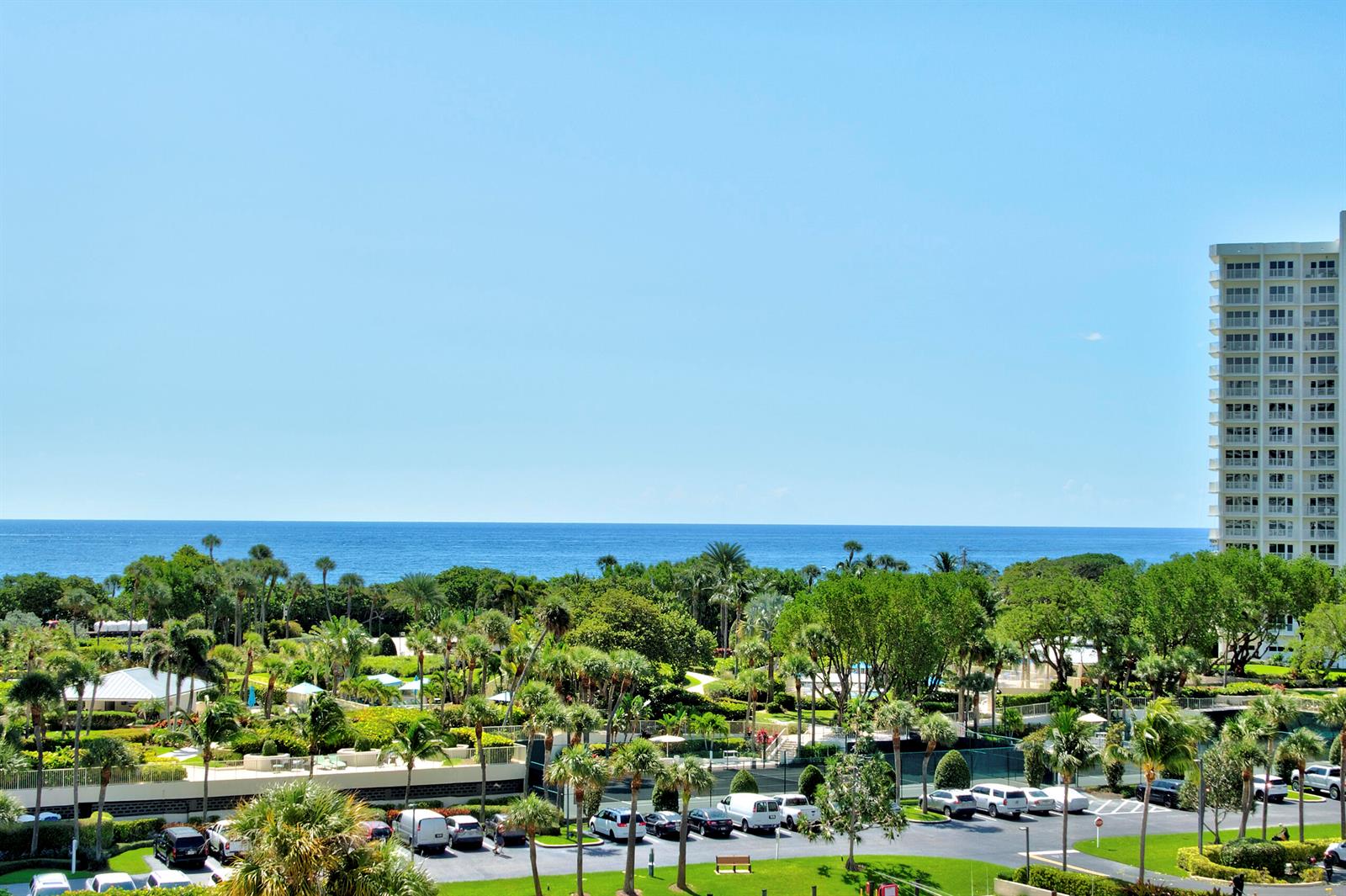 An elevated view of a lush tropical landscape with a tall building and the ocean — BOCA RATON, FL
