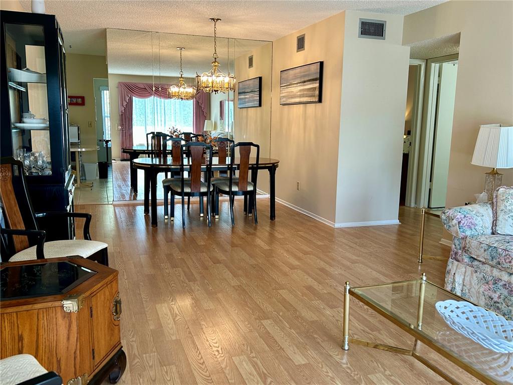 A dining area with a mirrored wall and chandelier sits adjacent to a living room — 2256 PHILIPPINE DRIVE UNIT 42, CLEARWATER, FL
