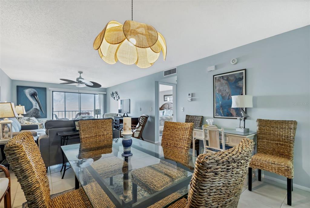 A dining area with a glass table and wicker chairs sits before a living room — 14459 RIVER BEACH DRIVE UNIT 129, PORT CHARLOTTE, FL