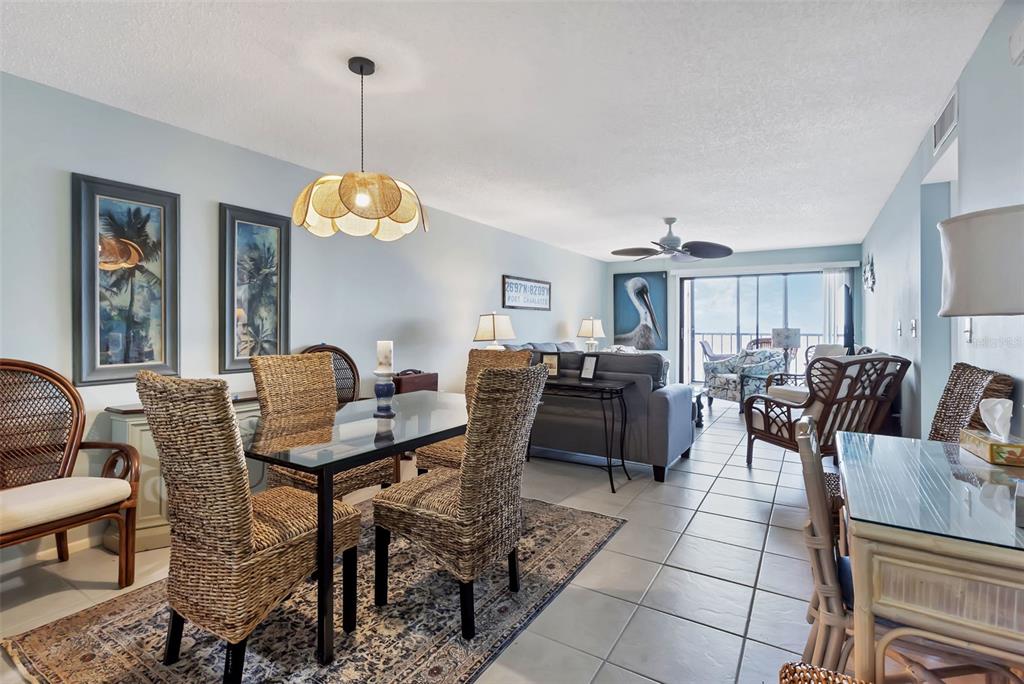 A dining area with wicker chairs and a glass table opens into a living room — 14459 RIVER BEACH DRIVE UNIT 129, PORT CHARLOTTE, FL
