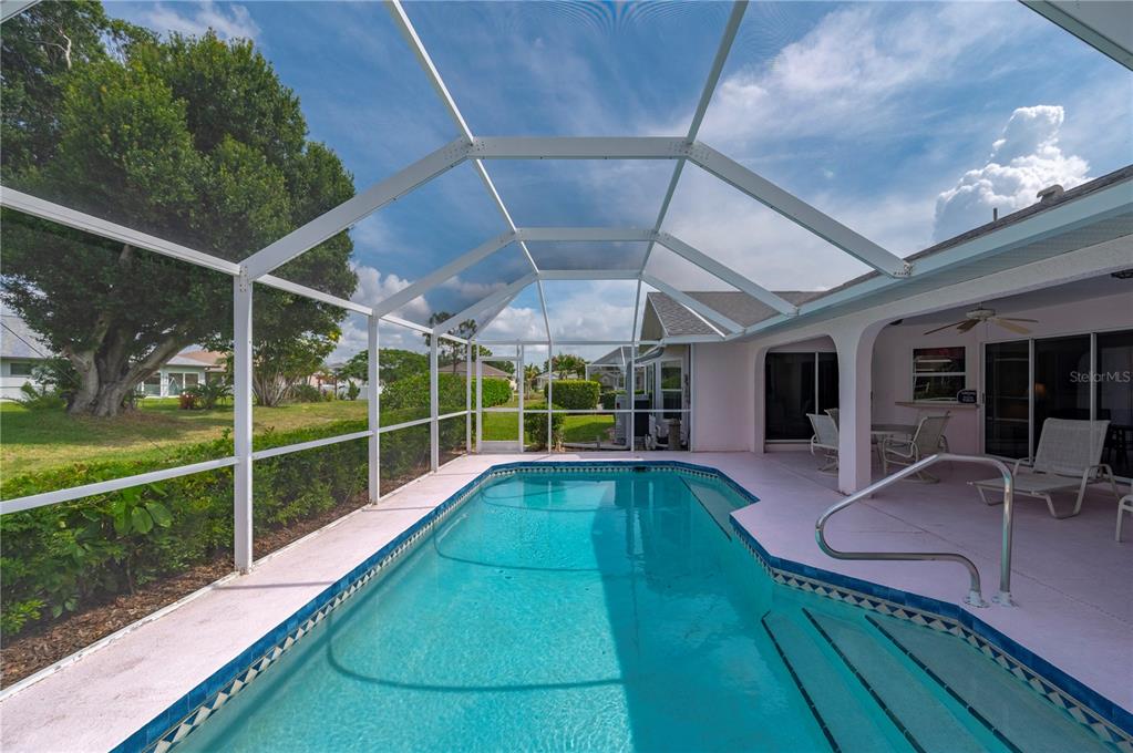 A swimming pool with a screened enclosure sits on a patio next to a house — 2231 HAMBURG LANE, PUNTA GORDA, FL