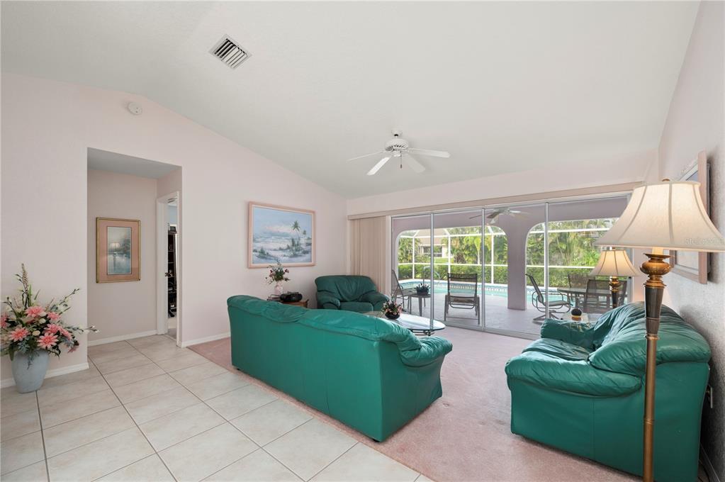 A living room with teal leather furniture, pink carpeting, and sliding doors to a pool — 2231 HAMBURG LANE, PUNTA GORDA, FL
