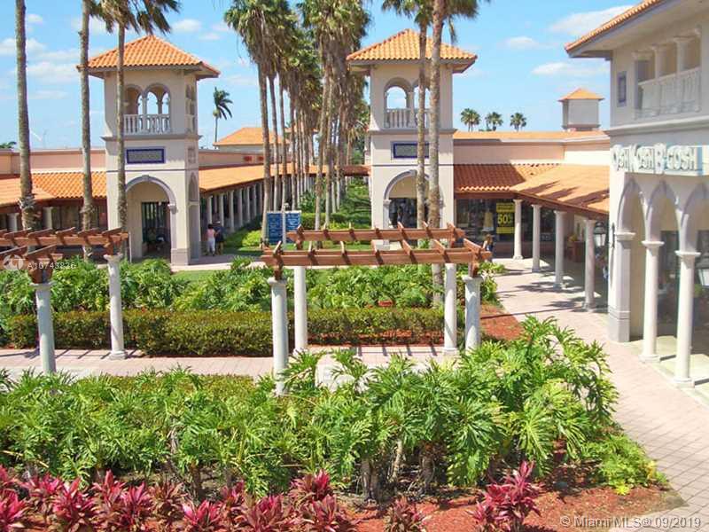 An outdoor shopping center courtyard features palm trees, a wooden pergola, and Mediterranean-style architecture — SW 376TH ST, Homestead FL 33035, HOMESTEAD, FL