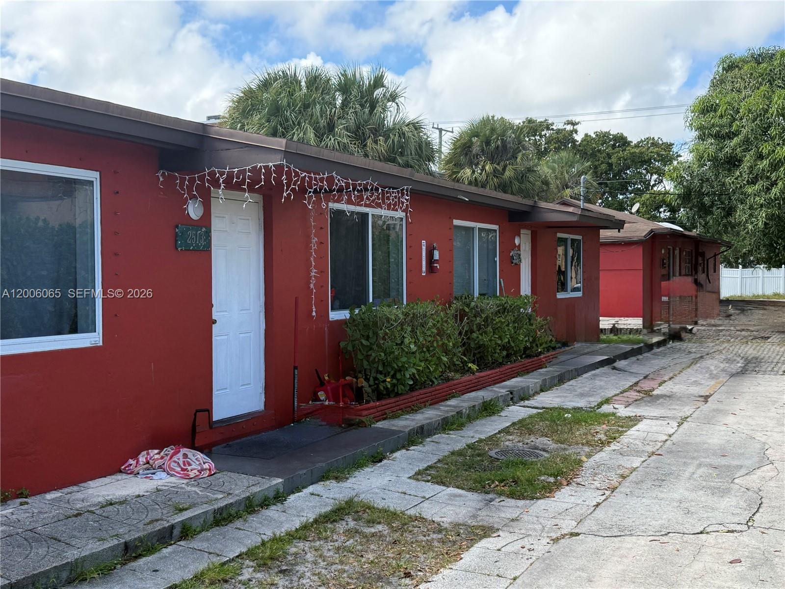 A red single-story building with white doors and windows sits along a paved driveway — 2513 Lincoln St, Hollywood FL 33020, HOLLYWOOD, FL