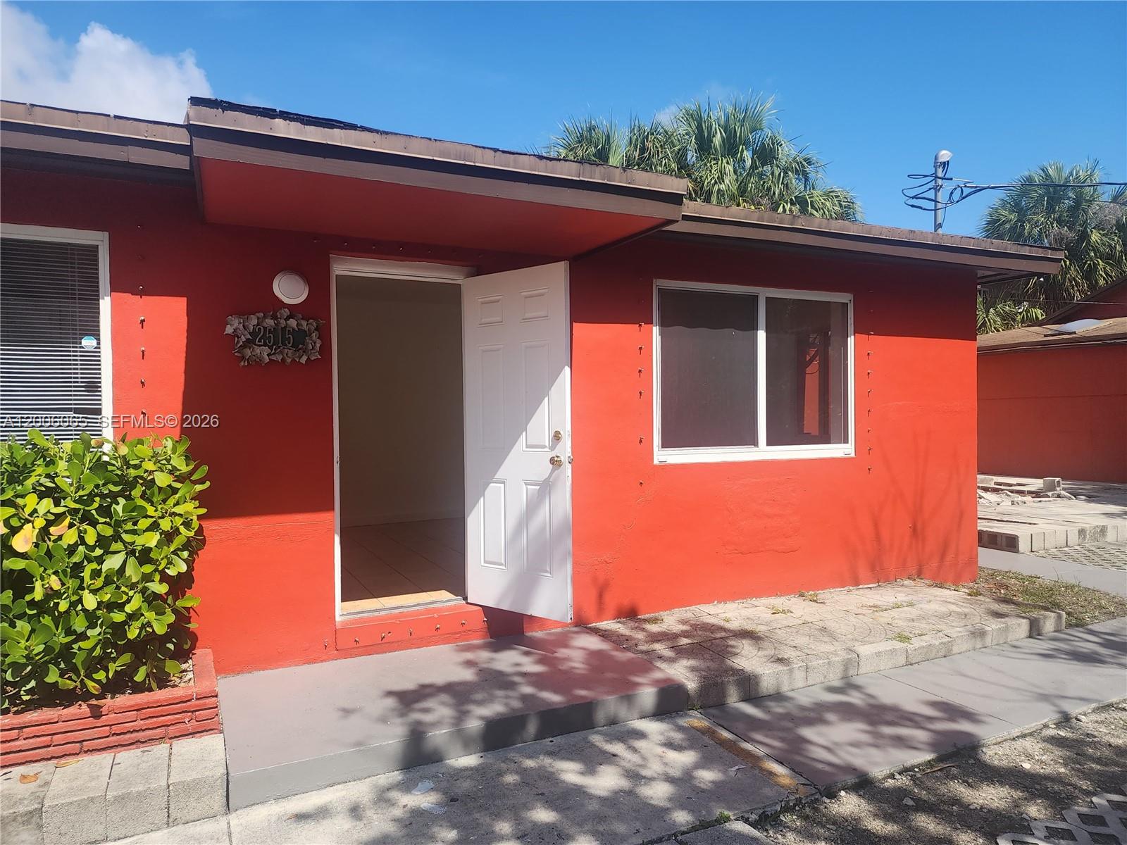 A red exterior wall features a white front door, a window, and a house number — 2513 Lincoln St, Hollywood FL 33020, HOLLYWOOD, FL