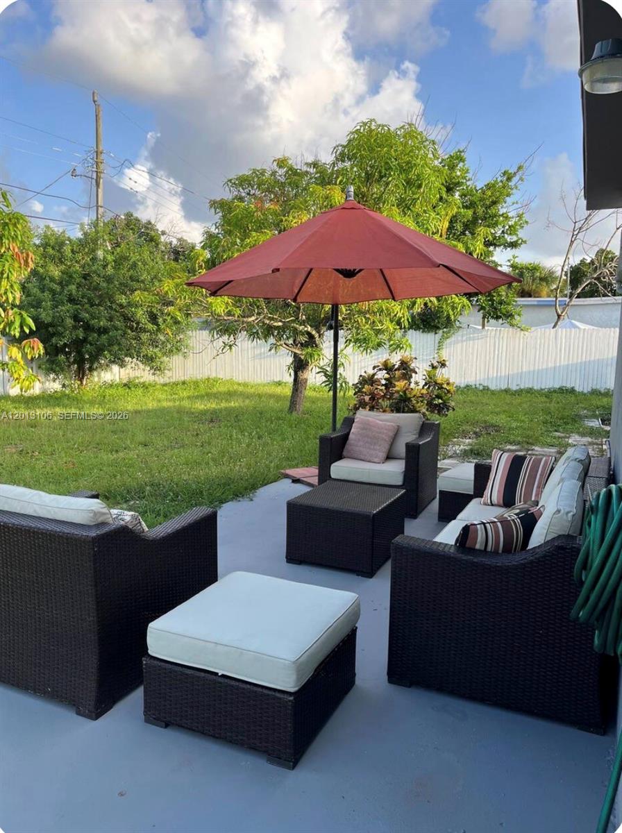 A patio features dark wicker furniture with light cushions and a red umbrella — 4720 NE 14th Ave, Pompano Beach FL 33064, POMPANO BEACH, FL