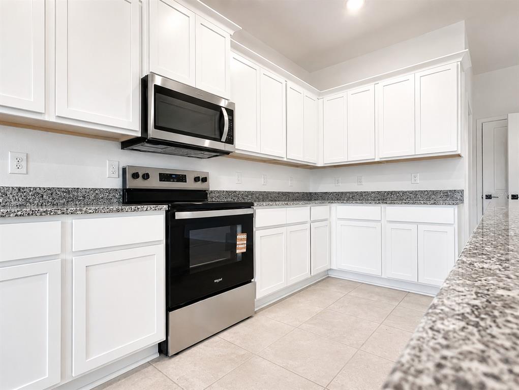A kitchen features white cabinets, granite countertops, and stainless steel appliances — 7587 BENT TREE LOOP, ST CLOUD, FL