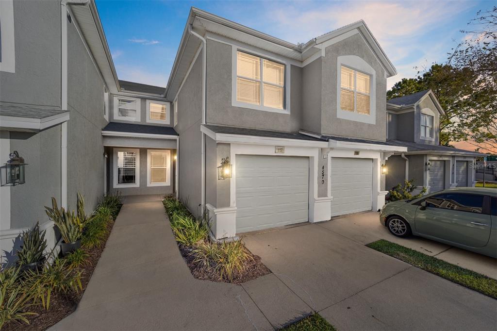 A two-story gray townhouse exterior features a concrete walkway, two garage doors, and a parked car — 4570 SW 52ND CIRCLE UNIT 107, OCALA, FL