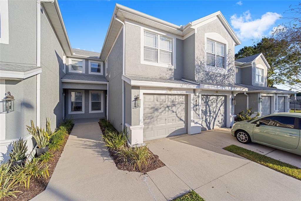 A two-story gray townhouse with a concrete driveway, two garage doors, and a front walkway — 4570 SW 52ND CIRCLE UNIT 107, OCALA, FL