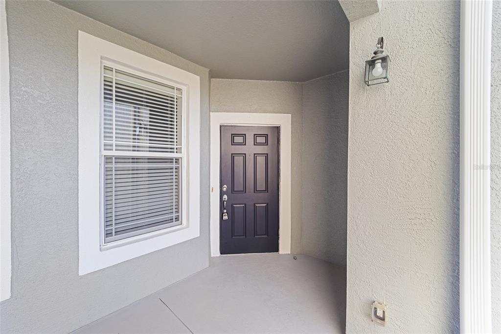 A covered entryway features a dark front door, a window with blinds, and a light — 4570 SW 52ND CIRCLE UNIT 107, OCALA, FL