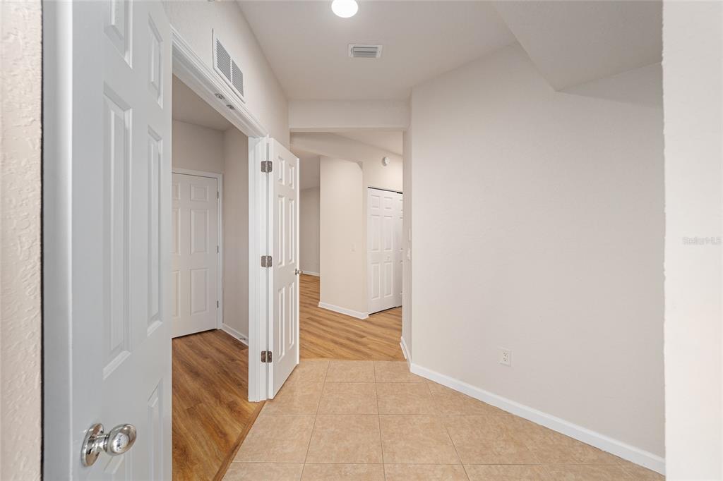 A tiled entryway leads into a hallway with wood-look flooring and white interior doors — 4570 SW 52ND CIRCLE UNIT 107, OCALA, FL