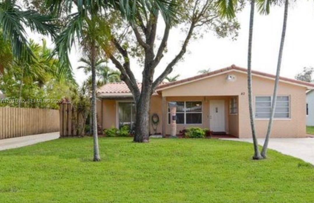 A concrete driveway leads to a small building entrance next to a wooden fence — 40 SE 8th St, Dania Beach FL 33004, DANIA BEACH, FL