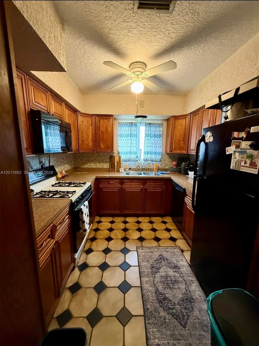 A living room features a beige sofa, a teal armchair, and tile flooring — 40 SE 8th St, Dania Beach FL 33004, DANIA BEACH, FL