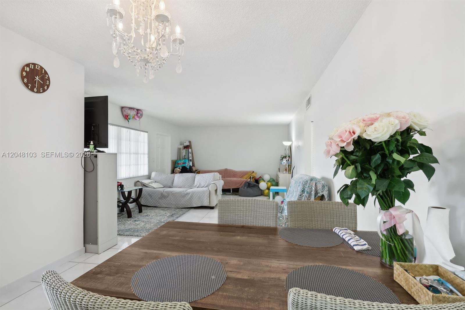 A dining area with a wooden table overlooks a living room with a white sofa — HALLANDALE BEACH, FL