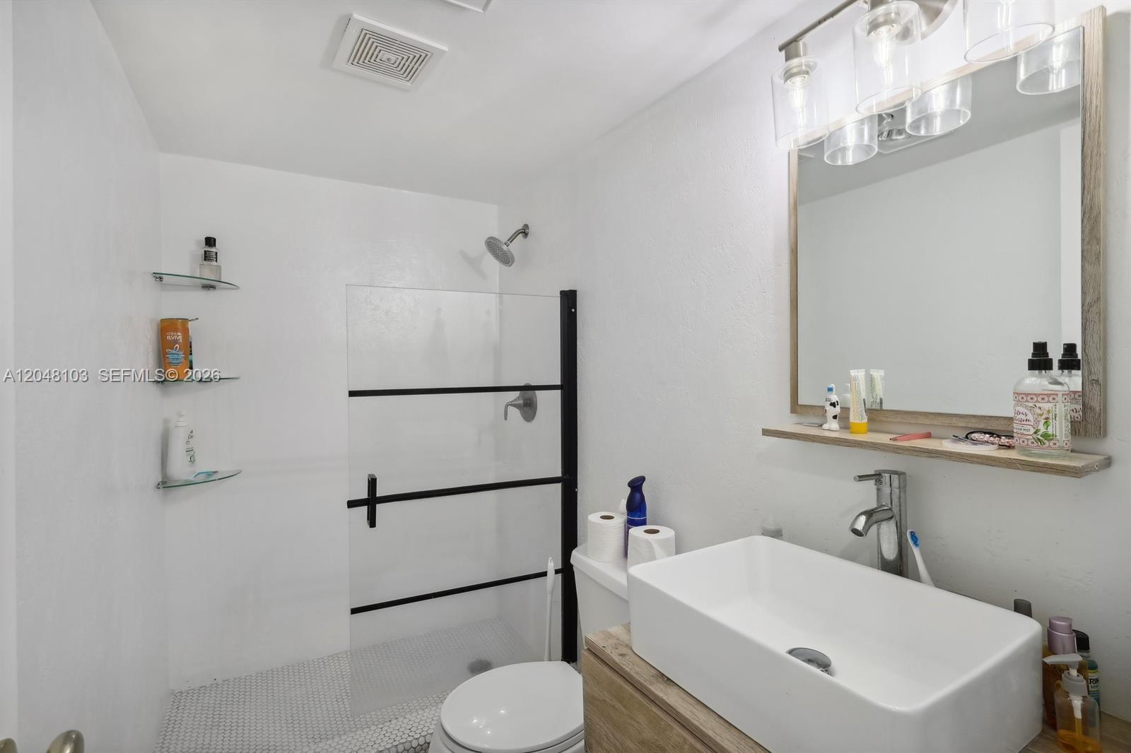 A bathroom features a walk-in shower with a glass door, a vessel sink, and shelving — HALLANDALE BEACH, FL