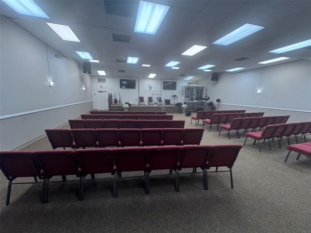 A large room with rows of red chairs facing a stage with musical instruments — 11601 S ORANGE BLOSSOM TRAIL UNIT 203, ORLANDO, FL